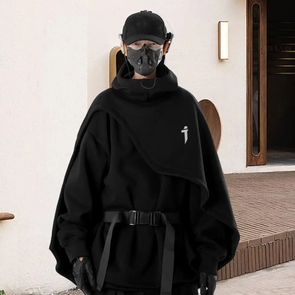Person wearing a black outfit with a hood and mask, standing in front of a building entrance.